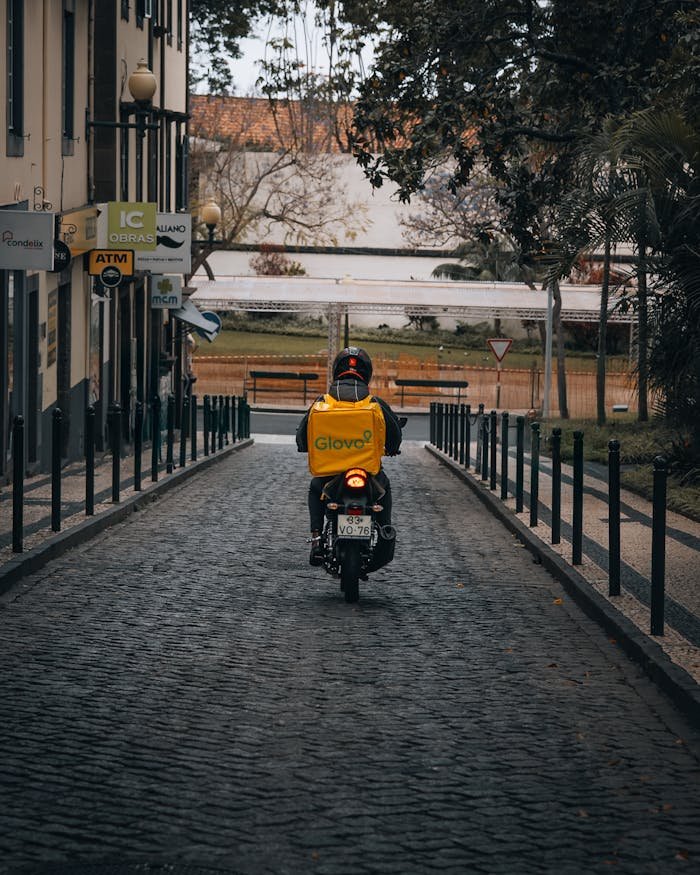 Delivery driver on a bike in a serene Madeira street. Vintage ambiance.